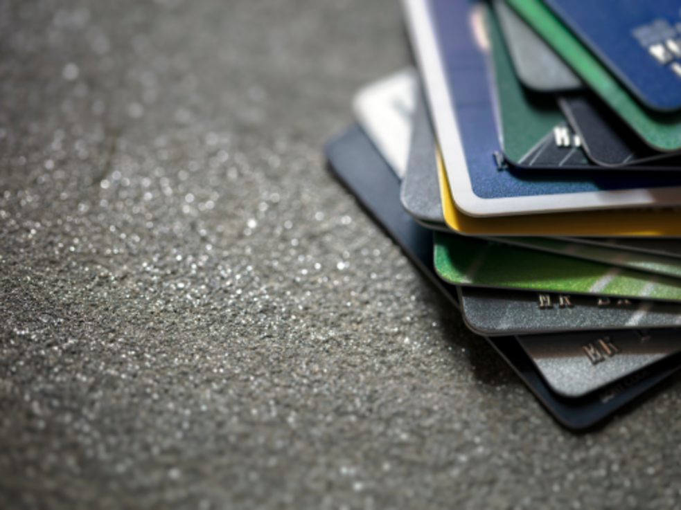 Ein Stapel Kreditkarten liegt auf einer strukturierten grauen Oberfläche.